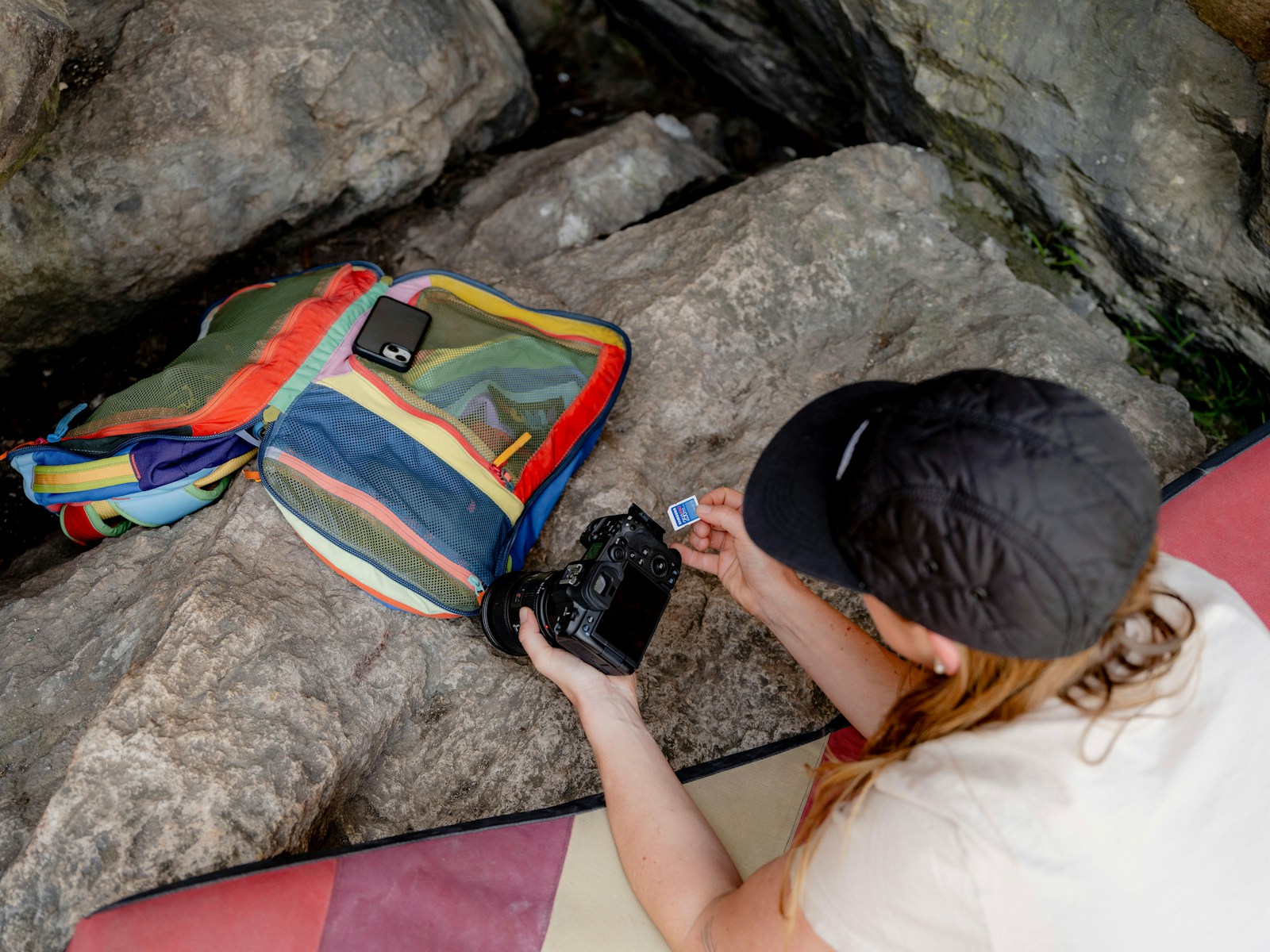 A person sitting on a rock with a camera